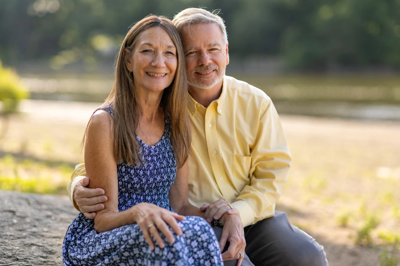 Cliff and Sue, founders of Masterpiece Journey, sitting together outdoors by a river